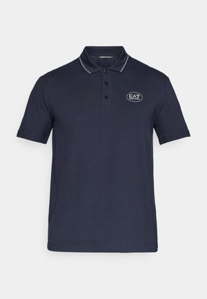 Polo majica u mornarsko plavoj boji izrađena od mekog pamuka, s klasičnim ovratnikom, plaketom s tri gumba i bijelim akcentnim prugom. EA7 logo na prsima.