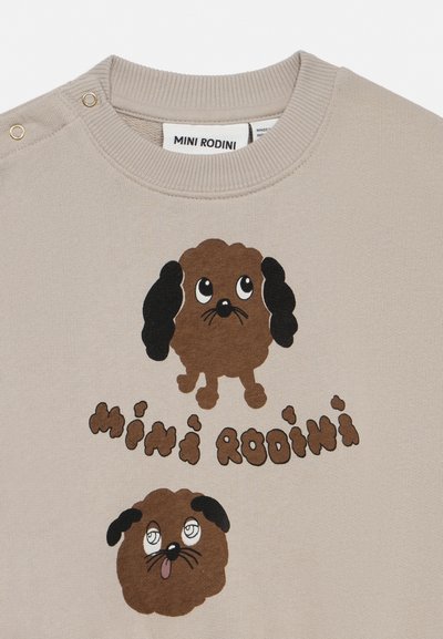 Beige genser med to tegneseriebrune hunder, en med svarte ører som ser opp, den andre med tungen ute, og teksten "Mini Rodini" i brunt.