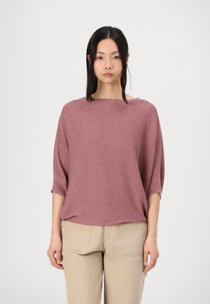 Lys rosa ribbet strikket topp med bred båtutringning og korte ermer, kombinert med beige bukser. Enkel, avslappet passform.