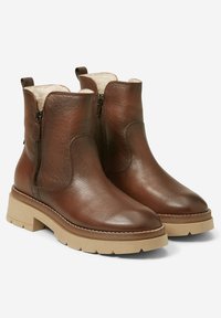 Botas de tobillo de cuero marrón con un acabado texturizado, cremalleras laterales y una suela gruesa beige. Interior forrado para mayor comodidad.