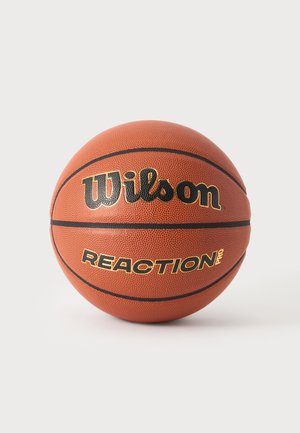 Balón de baloncesto Wilson Reaction Pro naranja con líneas negras y superficie texturizada sobre un fondo claro y liso.