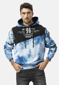 Sweatshirt met capuchon met een tie-dye blauw ontwerp, een zwart bovenstuk, frontale grafische tekst en geribde manchetten. Verstelbare capuchon met trekkoord.