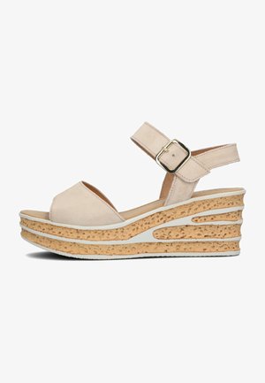 Beige Wildledersandalen mit Keilabsatz, offenem Zehenbereich, verstellbarem Knöchelriemen und einer strukturierten Korkplattform. Weiße Akzente im Keil-Design.