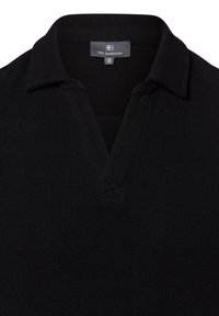 Schwarzer Pullover mit gerippter Textur, mit V-Ausschnitt und Kragen. Das Etikett zeigt die Marke "Nils Sundström" und die Größe "M 50".