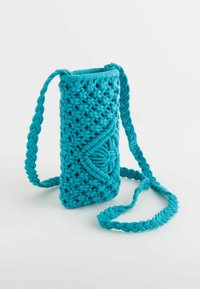 Turquoise knitted crossbody bag with a textured pattern, a braided strap, and a decorative lateral design element.