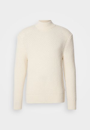 Maglione a maglia testurizzata color crema, con maniche lunghe e colletto alto a coste, polsini e orlo su sfondo bianco.