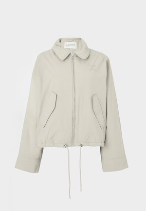 Light gray cropped jacket with a collar, front zipper, two pockets, and drawstring hem. Features subtle logo embroidery on the chest.