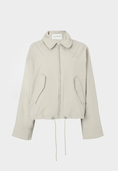 Ανοιχτό γκρι cropped μπουφάν με γιακά, φερμουάρ μπροστά, δύο τσέπες και ρυθμιζόμενο στρίφωμα με κορδόνι. Διαθέτει διακριτική κεντημένη λογότυπο στο στήθος.