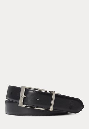 Ceinture en cuir noir avec boucle rectangulaire argentée, partiellement enroulée sur un fond clair.