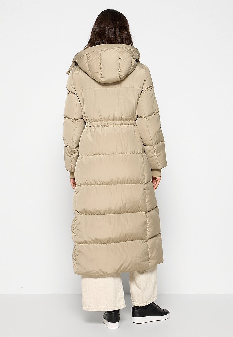 Manteau long beige en duvet avec un design matelassé, capuche, taille cintrée et poches latérales. Tissu lisse et brillant avec une coupe décontractée.
