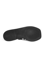 Semelle de chaussure en caoutchouc noir avec un motif texturé, comportant des rainures et un design plat pour l'adhérence. Fini lisse avec une apparence mate.