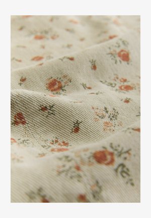 Hellbeiger Stoff mit einem floralen Muster in gedecktem Rot und Grün. Strukturierte Oberfläche mit sichtbarer Köperbindung und verstreuten kleinen Blumen.