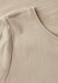 Beige bavlněné tričko s krátkým rukávem, kulatým výstřihem a hladkým povrchem. Viditelné švy podél výstřihu a švů na ramenou.