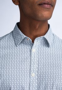 Lichtblauw gestippeld overhemd met een subtiel geometrisch ontwerp, voorzien van een button-down kraag en witte knopen, gemaakt van een lichtgewicht stof.