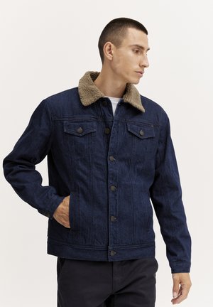 Denim jacket in dark navy with a tan faux shearling collar. Features two chest pockets and two side pockets, with metal button closures.