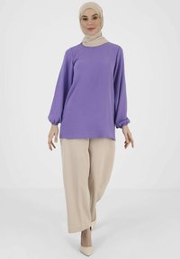 Purple long-sleeve top with gathered cuffs, paired with beige wide-leg pants and light-colored pointed shoes, against a plain white background.