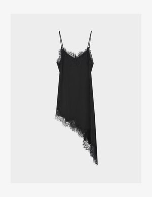 Sort asymmetrisk slip kjole med blondedetaljer, tynde spaghetti stropper og V-hals på en ensfarvet lys baggrund.