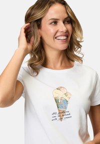 Hvid bomulds T-shirt med et grafisk motiv af en isvaffel med pastelfarvede is-scoops og tekst. Korte ærmer, klassisk rund halsudskæring.