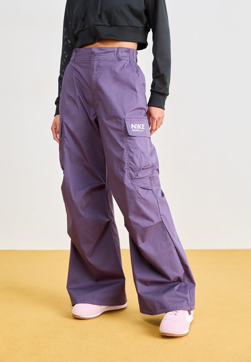 Purple cargo pants made of lightweight fabric, featuring a high waist, side pockets, and a white Nike logo on the right thigh.