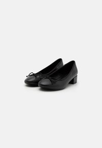 Czarne skórzane buty na średnim obcasie z okrągłym noskiem i ozdobną kokardką z przodu. Gładka tekstura i prosty, elegancki design.
