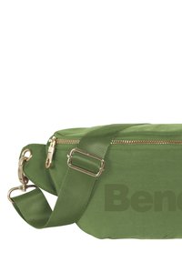 Groene stoffen tas met een ritsluiting, verstelbare schouderband, gouden hardware en een grote bedrukt merknaam in een donkerder groen.