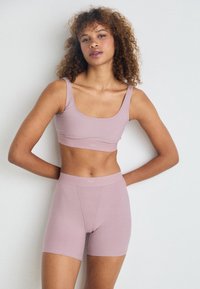 Set di reggiseno e pantaloni sportivi di colore viola chiaro realizzati in un tessuto elasticizzato. Il reggiseno presenta una scollatura ampia; i pantaloni hanno una vita liscia e uno stile aderente.