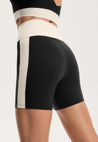 Črne aktivne kratke hlače z visokim kremnim pasom in stranskimi paneli. Narejene iz raztegljivega materiala, z prilegajočim krojem in čistimi linijami.