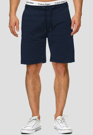 Navy blue cotton shorts with an elastic waistband featuring a drawstring. Subtle stitched accents and a relaxed fit for comfort.