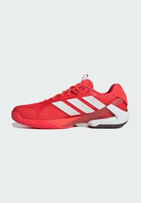 Czerwone buty sportowe z przewiewną siateczką, białym paskowanym wzorem, teksturowaną podeszwą oraz wspierającym zapiętkiem.