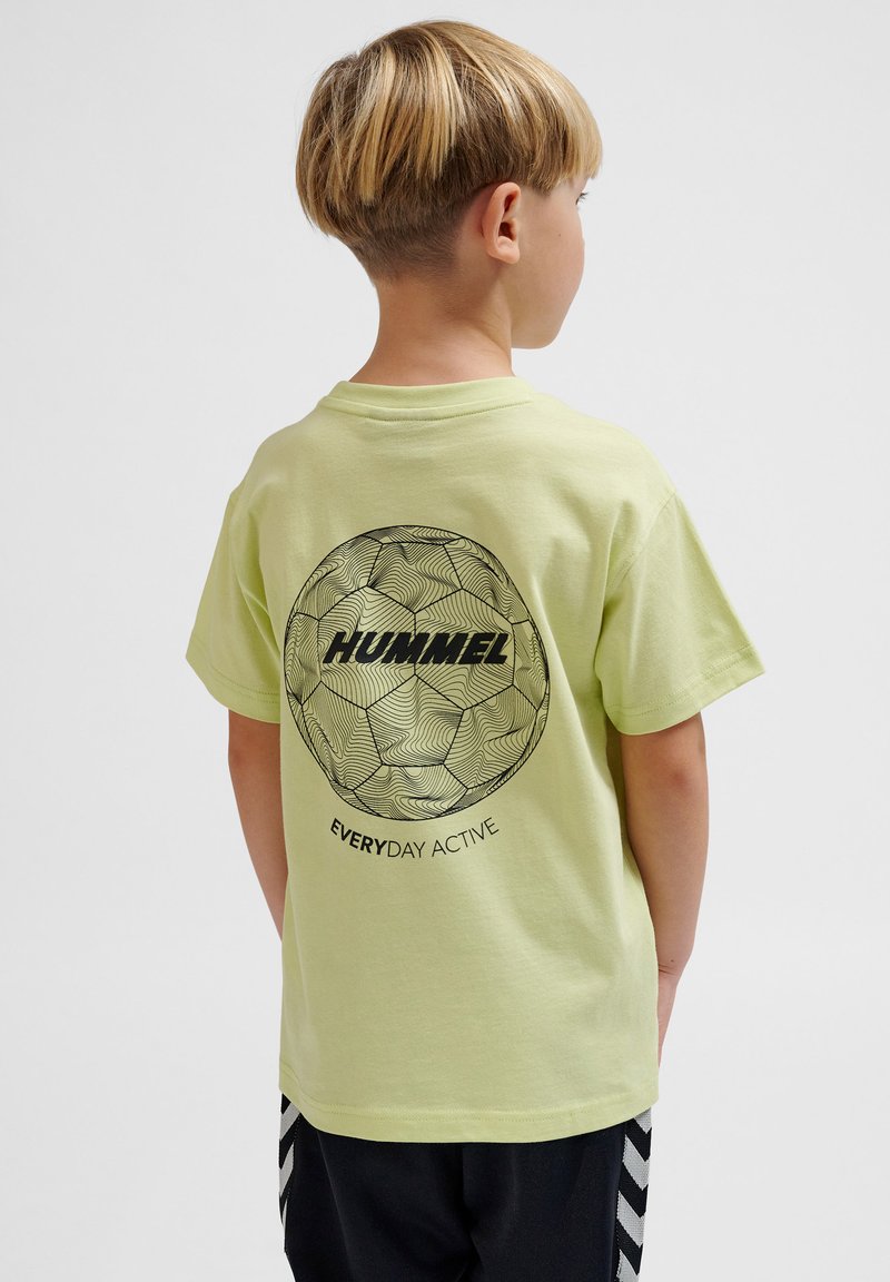 Lys grøn bomulds t-shirt med et stort sort grafisk motiv af en fodbold og teksten "HUMMEL EVERYDAY ACTIVE" på ryggen.