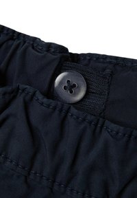 Tissu bleu marine foncé affichant un gros plan d'une ceinture avec un bouton transparent brillant et des détails élastiques cousus. Texture lisse, design minimaliste.
