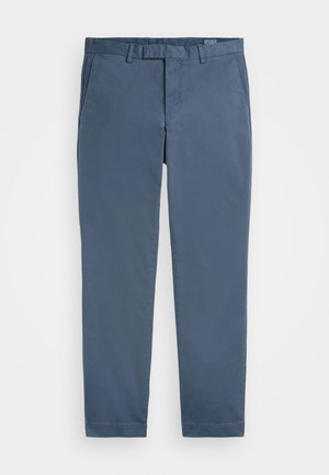 Pantalon chino en un mélange coton bleu foncé, avec un design à l'avant plat, des poches latérales et une coupe droite, fini avec des ourlets cousus.