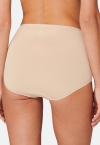 Beige Unterwäsche mit hoher Taille aus einem glatten, dehnbaren Material und nahtlosen Kanten, entworfen für Komfort und eine dezente Passform.