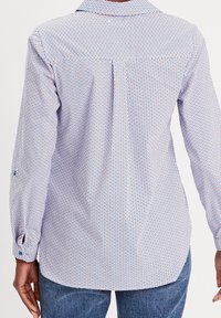 Long-sleeve shirt in white with a geometric blue and orange pattern. Features a collar and button detail on the sleeves.