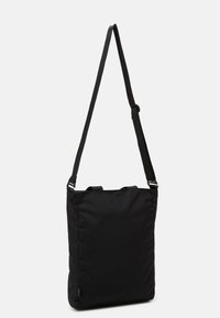 Svart nylon axelväska med rektangulär form, med justerbara remmar, två överhandtag och en slät yta.