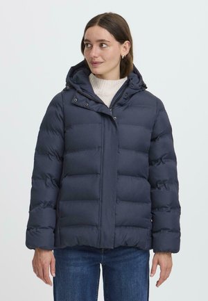 Veste matelassée marine avec capuche, présentant une texture matelassée et une fermeture à pression. Le design comprend un col haut et une fermeture éclair à l'avant.