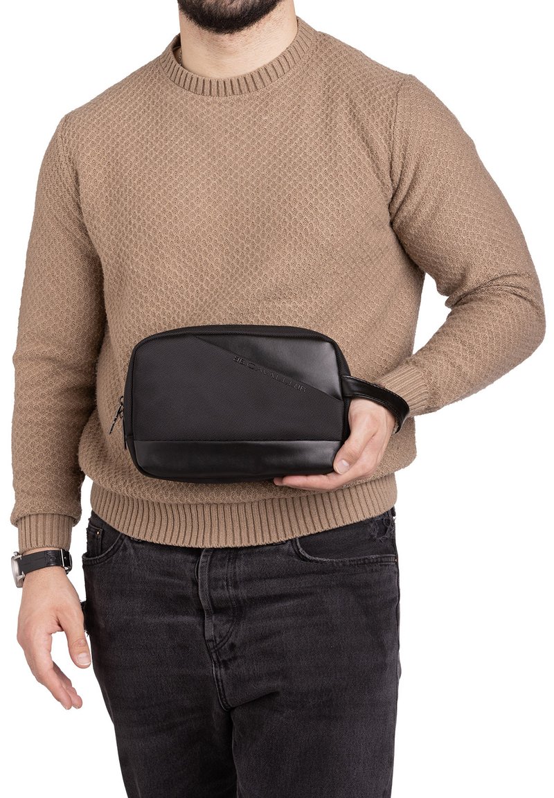 Zwarte toilettas met een gestructureerd bovenpaneel en een glad onderpaneel, ritssluiting en een polsband voor gemakkelijke draagbaarheid.