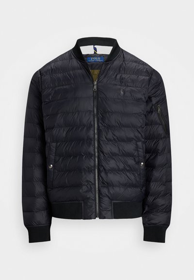 Svart, kviltad bomberjacka med ribbade cuffs och nederkant, dragkedja fram, två sidofickor och en ficka på ärmen med dragkedja.