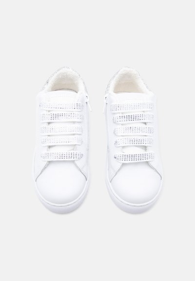 Ζεύγος λευκών αθλητικών παπουτσιών με πέντε λαμπερούς ιμάντες με βέλκρο και πλαϊνά φερμουάρ, με μαλακή, χνουδωτή εσωτερική επένδυση.