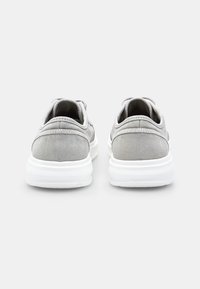 Sneakers in tela grigia con superficie texturizzata, suole in gomma bianca e cuciture tono su tono. Presentano una punta arrotondata e chiusura con lacci.