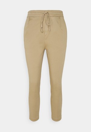 Pantalon beige slim fit avec taille élastique et cordon, doté de poches latérales et d'une cheville effilée.
