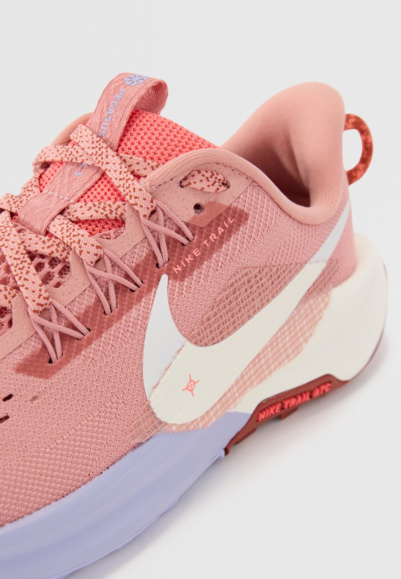 Nike Trailrunning-Schuh mit pinkem Mesh-Obermaterial, weißem Swoosh-Logo, strukturierten Schnürsenkeln und einer helllila Sohle mit roten Akzenten.