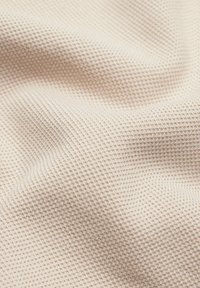 Teksturowana, beżowa tkanina o wzorze waflowym, prezentująca miękką, gładką powierzchnię i subtelną poświatę; lekka i łatwo układająca się.