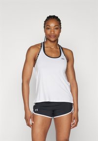 Canottiera atletica bianca con accenti neri e logo, presenta spalline regolabili e una vestibilità ampia, abbinata a pantaloni corti neri con rifiniture bianche.