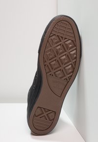 Sneaker nera in tela con suola in gomma testurizzata. Presenta un motivo di trazione geometrico e il logo del marchio sulla suola.