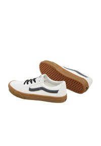 Hvide lærreds sneakers med sorte snørebånd, en marineblå sidekant og en brun gummisål med et tekstureret grebsmønster.