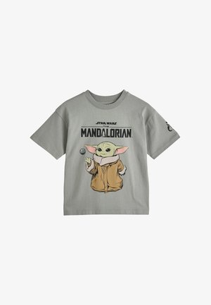 Svetlosivé tričko s postavičkou Baby Yodu v hnedom plášti a nápisom "Star Wars The Mandalorian" nad tým na prednej strane.