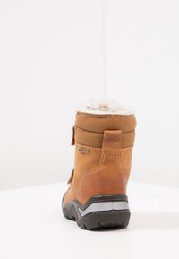 Brązowy wodoodporny but z miękką, kremową podszewką. Posiada skórzany cholewkę o teksturowanej powierzchni, solidną gumową podeszwę oraz detale w postaci przeszyć.