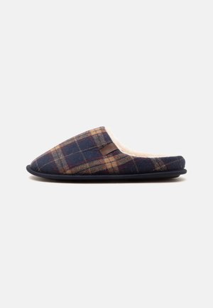 Chausson à enfiler à carreaux bleu marine et marron avec une doublure intérieure douce couleur crème et une semelle noire, montré de côté sur un fond clair.