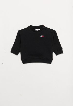 Sweat-shirt court noir avec manches courtes et poignets côtelés, doté d'un petit patch logo Tommy Hilfiger sur la poitrine et de boutons à l'épaule.
